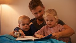 Dad reading with son and daughter